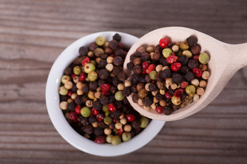 Pepper mixture on spoon over wooden background