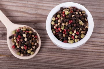 Pepper mixture on spoon over wooden background