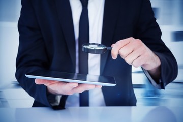 Composite image of businessman looking at his tablet
