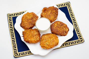 Potato pancakes with sour cream on the white plate
