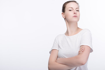 Fototapeta premium Junge hübsche selbstsichere Frau im weissen Shirt und verschränkten Armen