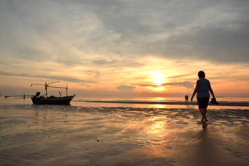 sunrise on beach with boat and people