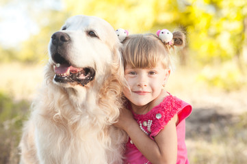 Cute kid girl 3-4 year old with labrador retriever outdoors. Childhood.