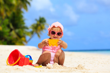 cute little girl playing with sand on the beach