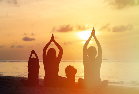 Family Silhouettes Doing Yoga At Sunset