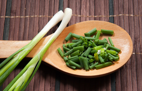 Chopped green  onions and spoon on a wooden