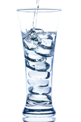 pouring water in an elegant tall glass with ice and water drops on white background