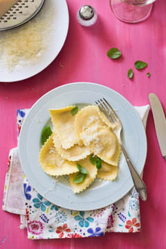 Italian Ravioli Served with Basil and Parmesan Cheese, Rose Painted Table on Background