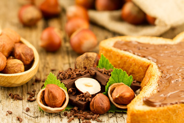 hazelnut with chocolate, toast and green leaves on old wooden background