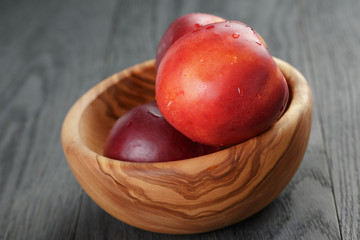 Fototapeta na wymiar nectarines in olive wood bowl on oak table