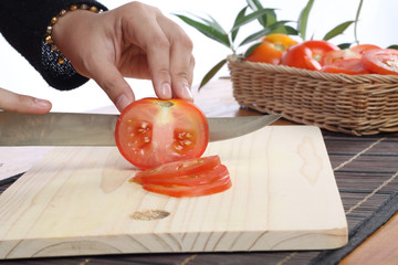 tomatoes cut by a kitchen knife on a wooden board