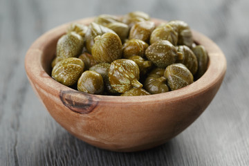 marinated capers in olive bowl on wood table