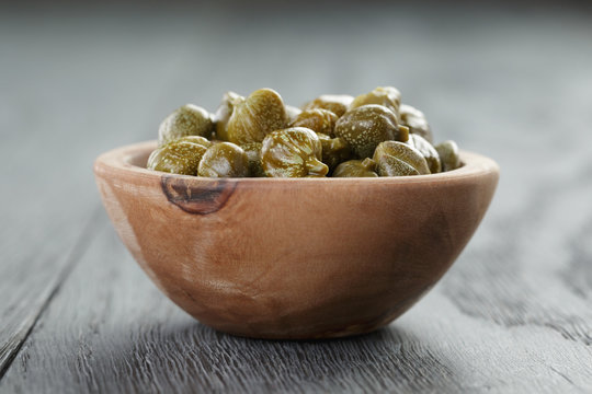 marinated capers in olive bowl on wood table