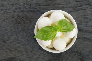 small balls of mozzarella in bowl with basil