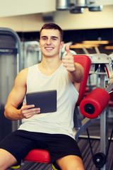 Fototapeta na wymiar smiling young man with tablet pc computer in gym