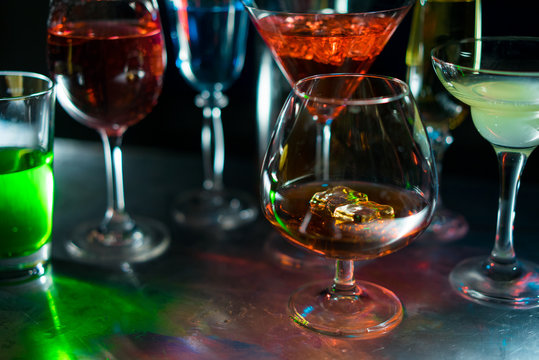 
A glass of cognac on the background glasses with drinks of various colors