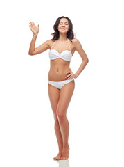 happy young woman in white swimsuit waving hand