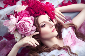 Obraz na płótnie Canvas beautiful woman in a wreath of peonies lies among petals