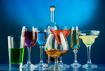 Glasses with alcohol different shapes on a blue background