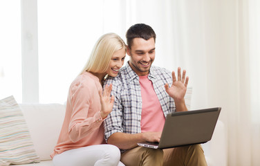 smiling happy couple with laptop computer at home