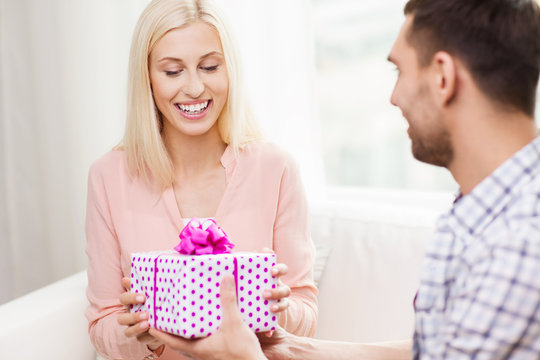 happy man giving woman gift box at home