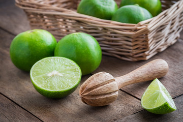 Wooden squeezer and lime on table