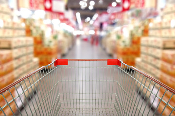 View from shopping cart trolley basket at supermarket self-service grocery shop. Retail. Blurred...