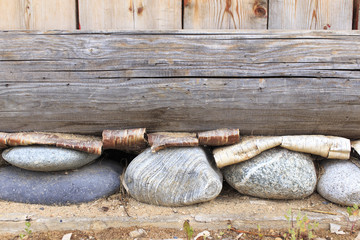 Foundation. layered Foundation of a house made of wood, stones and bark