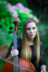 Beautiful blonde girl playing cello in black dress