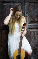 Fototapeta na wymiar Beautiful blonde girl playing guitar in white dress