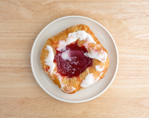 Raspberry danish on a small plate atop wood table top view