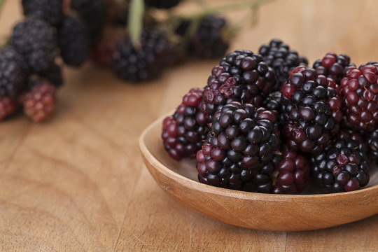 Blackberries in a spoon on wooden background
