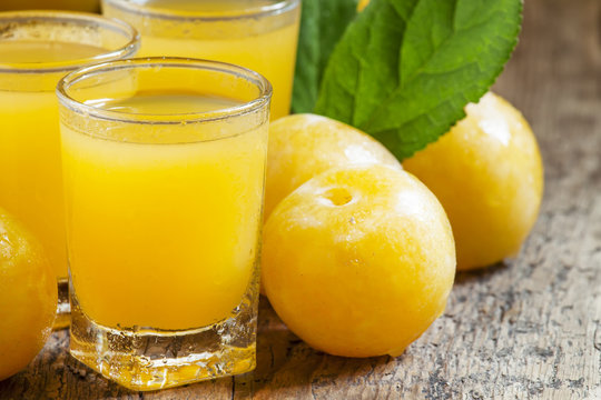 Delicious fresh juice of yellow sweet plums in a glass on the ol