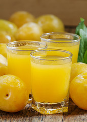 Delicious fresh juice of yellow sweet plums in a glass on the ol