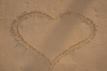 Heart drawn in the sand. Beach background. Top view