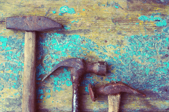 Three old rusty hammers on the blue painted wooden surface. Old tool