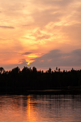 Fototapeta premium Fiery sunset at lakeside and silhouette forest