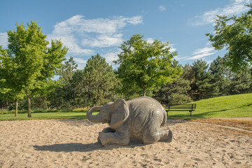 Elephant Playground Equipment in sandbox with blue sky and green trees
