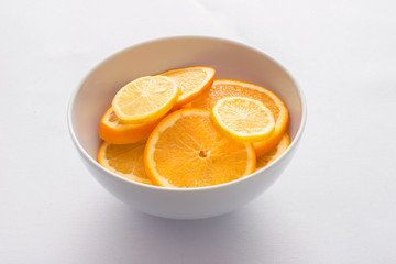 orange and lemon slices in a white bowl 