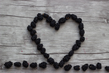 Schwarze Brombeeren auf Holzuntergrund zeigt Herz