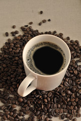 White ceramic coffee mug with coffee beans on cloth sack