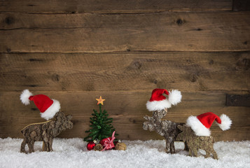 Weihnachten Dekoration aus Holz mit Rentiera und Santa Claus Mützen in rot weiß mit Tannenbaum.