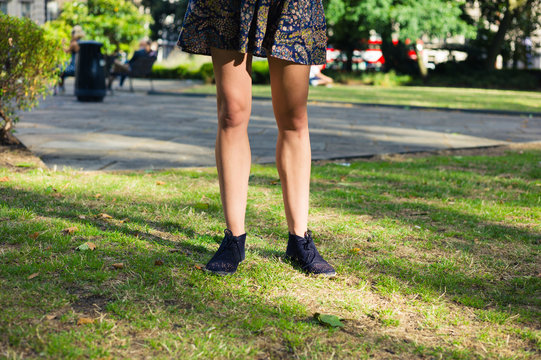 Legs of young woman standing on grass in park