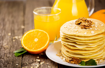 delicious pancakes on wooden table with orange and orange juice