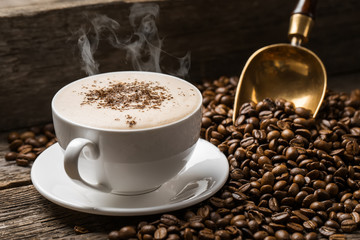 Close-up of coffee cup with roasted coffee beans on wooden background.