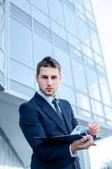 Businessman using a digital tablet computer, standing in front of his office.