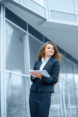 Fototapeta premium Successful businesswoman or entrepreneur using a digital tablet computer, standing in front of his office.