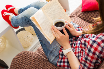 Woman sitting on the sofa reading a book holding her coffee mug