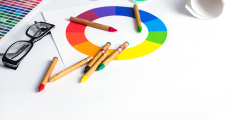 color pencils, colored palette and glasses on wooden table