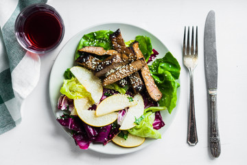 Sliced meat steak with green salad and pears